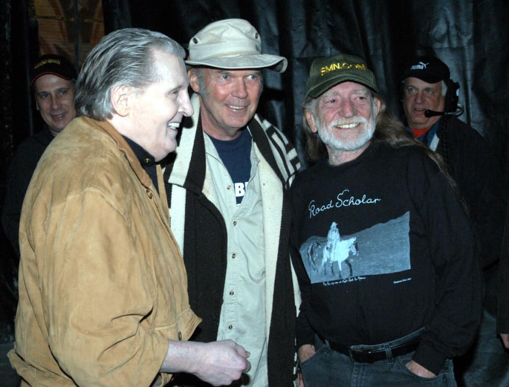 Willie Nelson standing with Neil Young. Willie is wearing the Minimum Wage Art shirt "Road Scholar" that we printed.